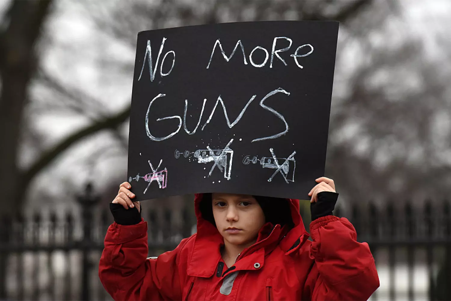 A Child's Protest: Young Girl Holds 'No More Guns' Sign at Anti-Shooting Rally A solemn-looking teenage girl holds a handmade 'No More Guns' protest sign at a March for Our Lives demonstration against gun violence