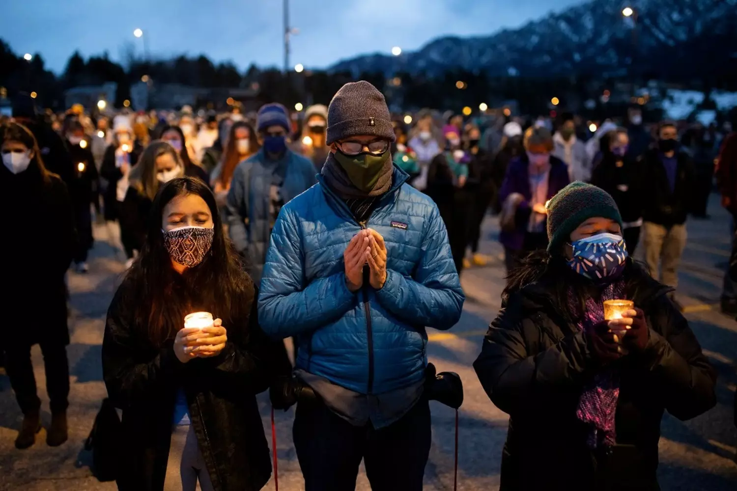 Candles in the Darkness: America Mourns Another Mass Shooting Tragedy A crowd holding candles during a vigil for victims of a mass shooting, their faces illuminated by the soft glow as they stand in silent remembrance