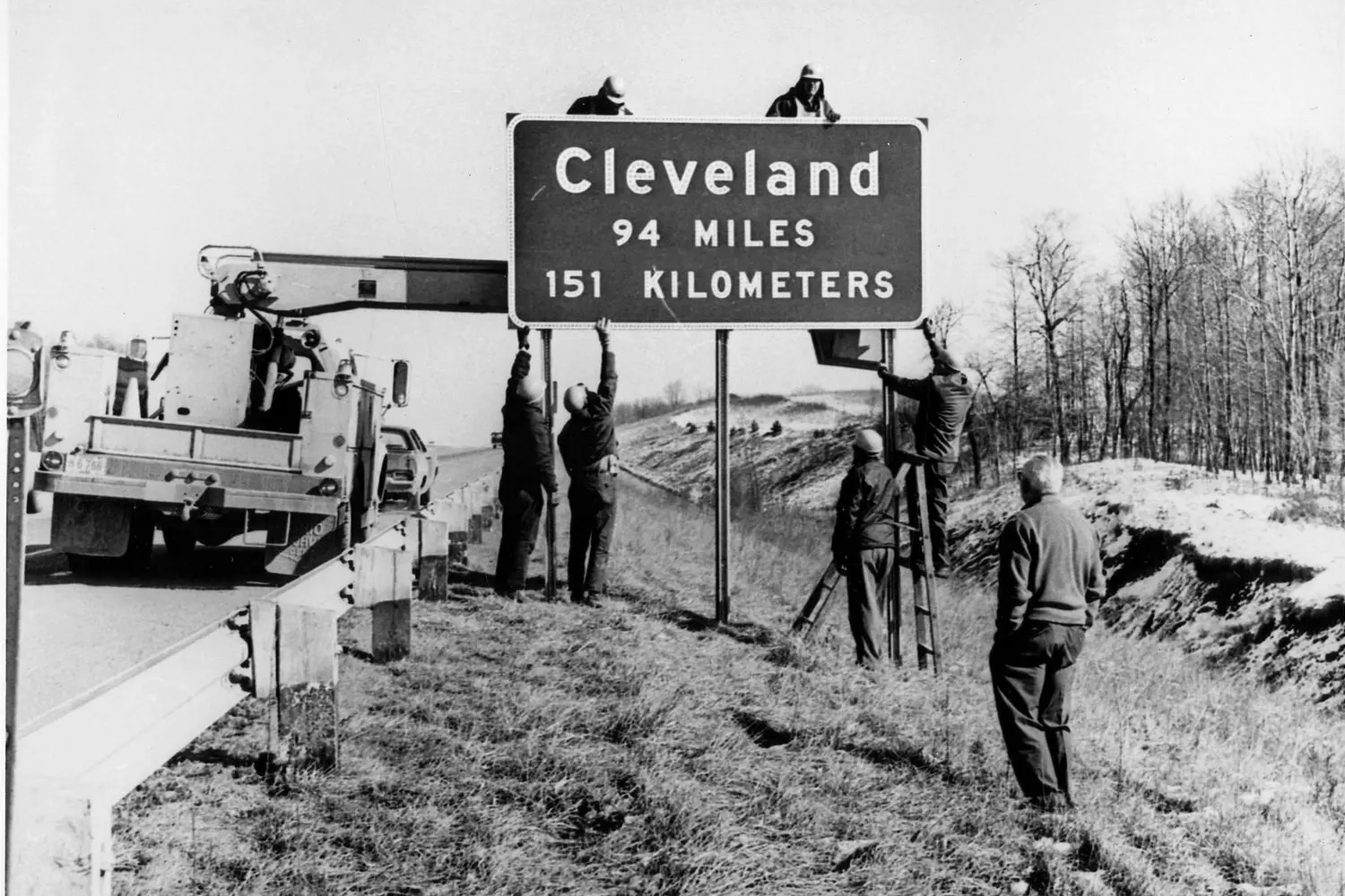 Changing the Road Signs: A Glimpse into America's Evolving Highway System Workers replacing vintage road signs in the USA, showcasing the transition in transportation infrastructure