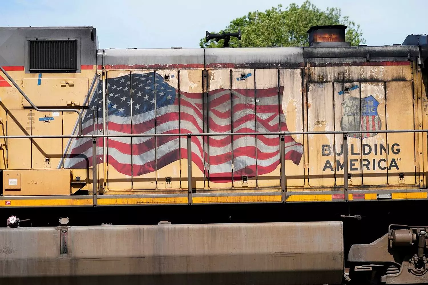 Symbol of Motion: Locomotive with the American Flag A powerful American locomotive on the tracks with a waving USA flag against a landscape background