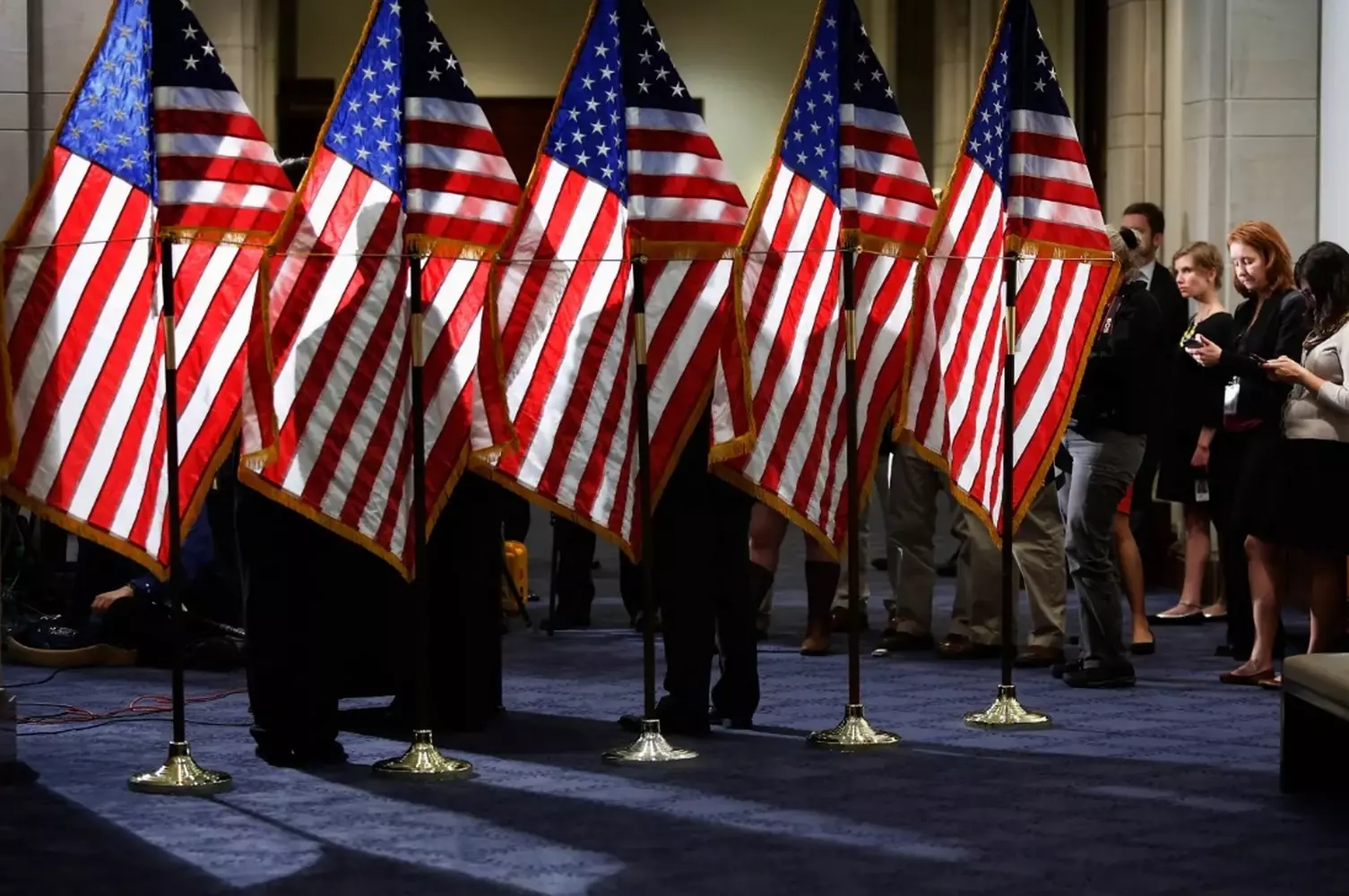 Multiple American flags displayed in the grand lobby of the White House A majestic row of large American flags standing in the elegant, spacious lobby of the White House, with polished floors and classical architecture
