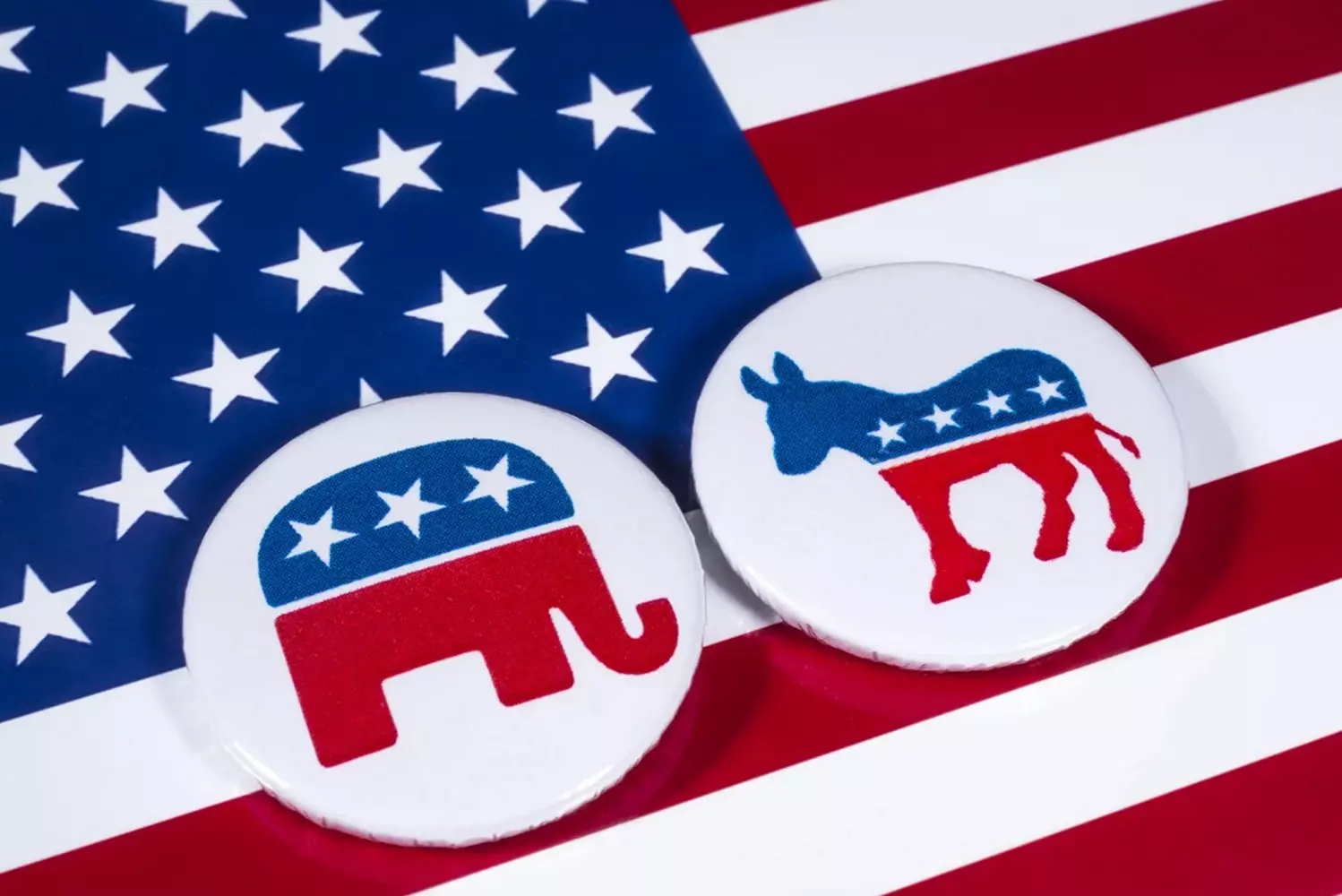 Democratic and Republican party pins on the US flag background Official party pins of the US Democratic (donkey) and Republican (elephant) parties placed side by side on the stars and stripes of the American flag