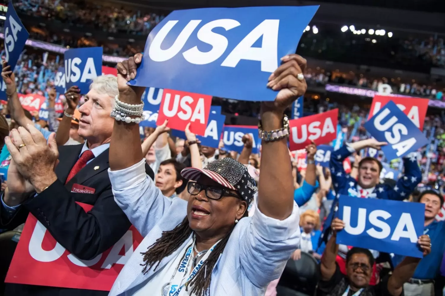 Political rally in the USA: people with election signs and American flags A diverse crowd of people at a political rally in the United States, holding handmade signs with election slogans and waving American flags
