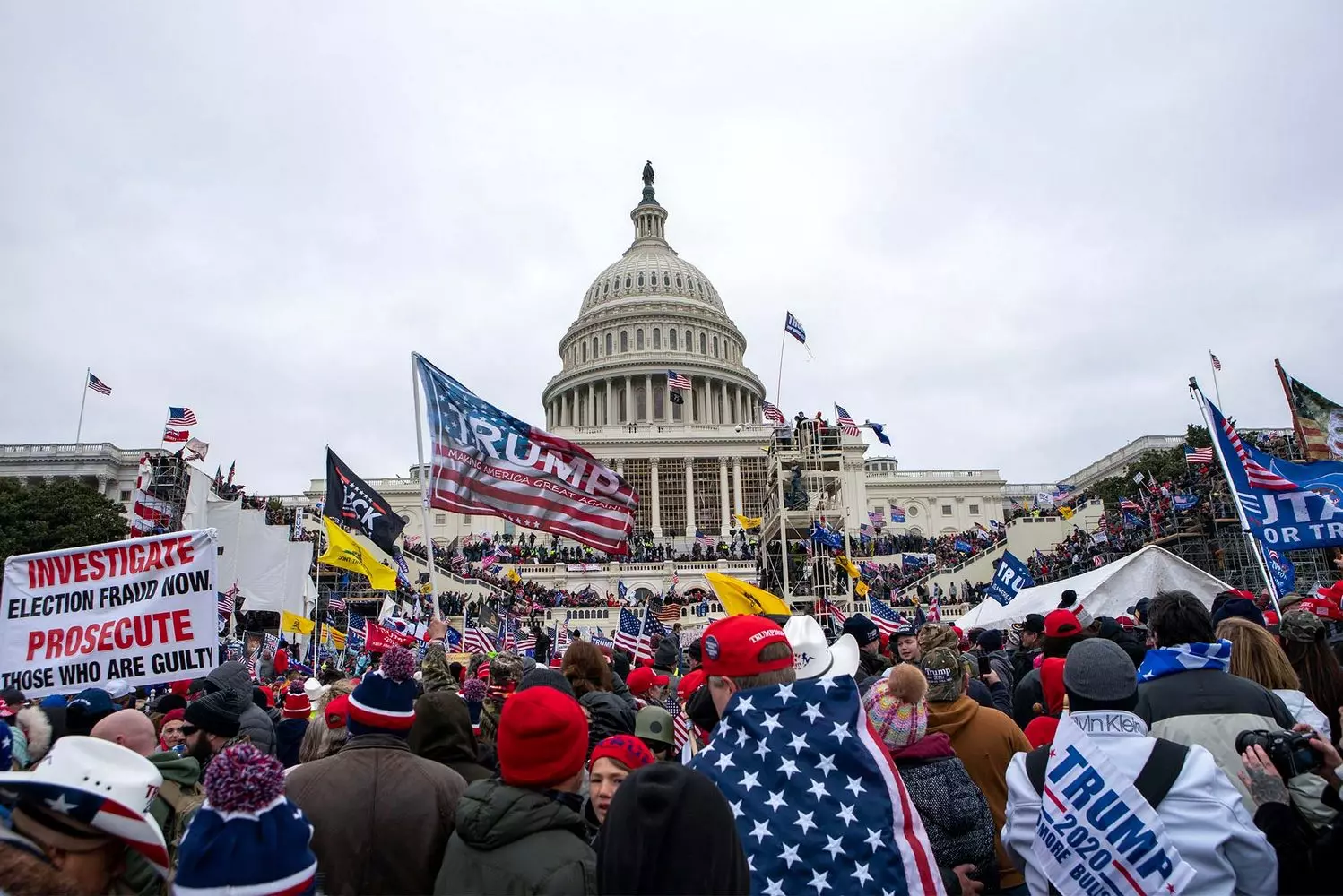 Political rally in the USA: people with election signs and American flags A diverse crowd of people at a political rally in the United States, holding handmade signs with election slogans and waving American flags