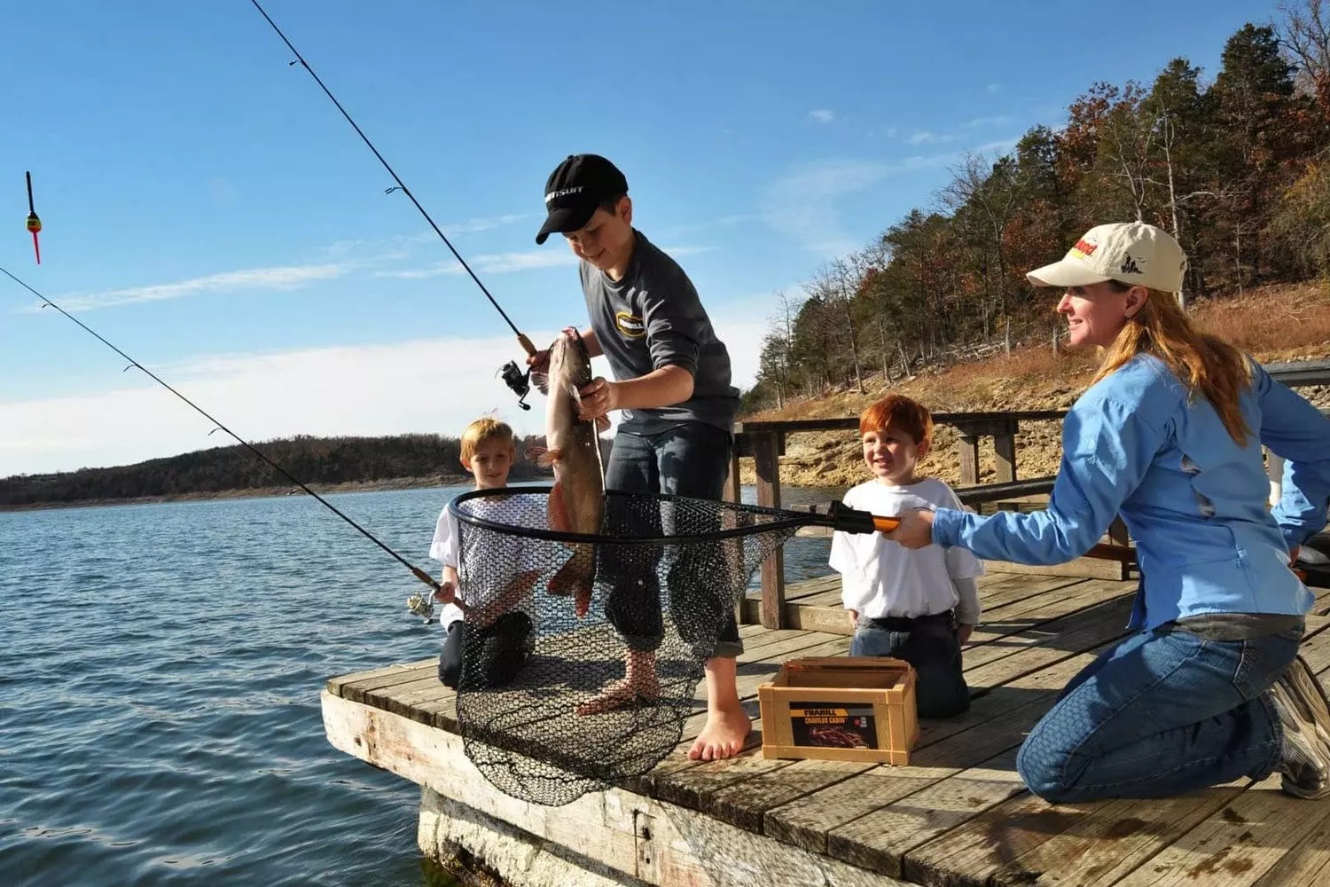 Семья ловит рыбу с пирса на озере в США на закате