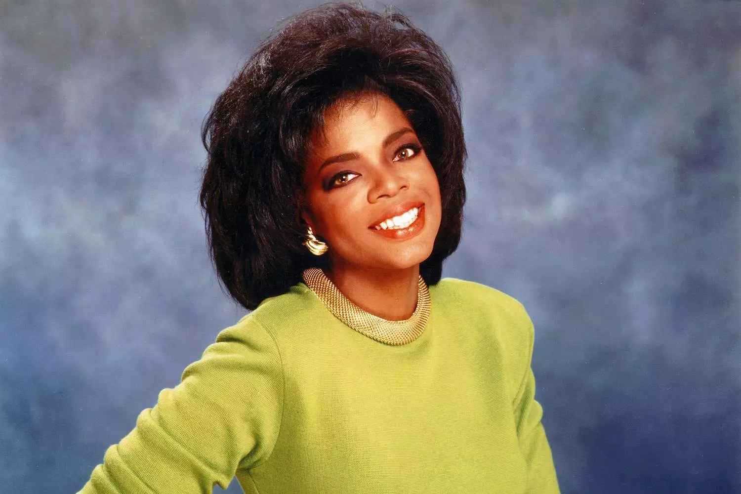 Становление Опры: Уверенность, харизма и фирменная прическа Опра Уинфри 1980-х с пышной афро-прической и харизматичной улыбкой