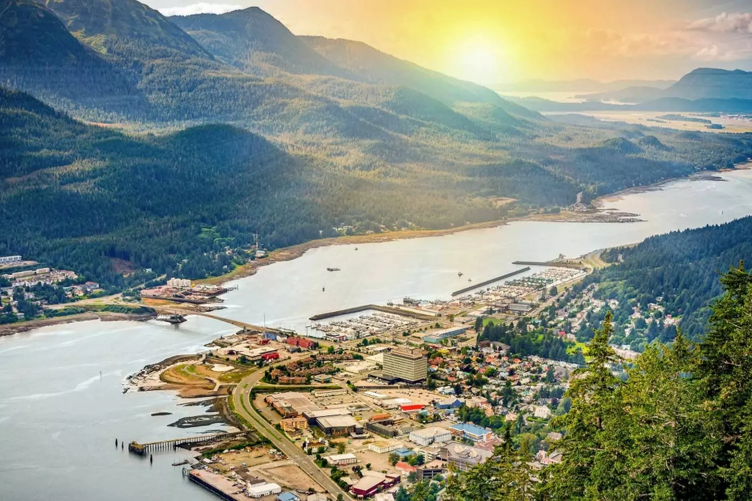 Juneau, Alaska: Where Mountains Meet the Sea Panoramic view of Juneau, Alaska's capital city, nestled between steep green mountains and the sparkling waters of Gastineau Channel, with cruise ships docked in the harbor