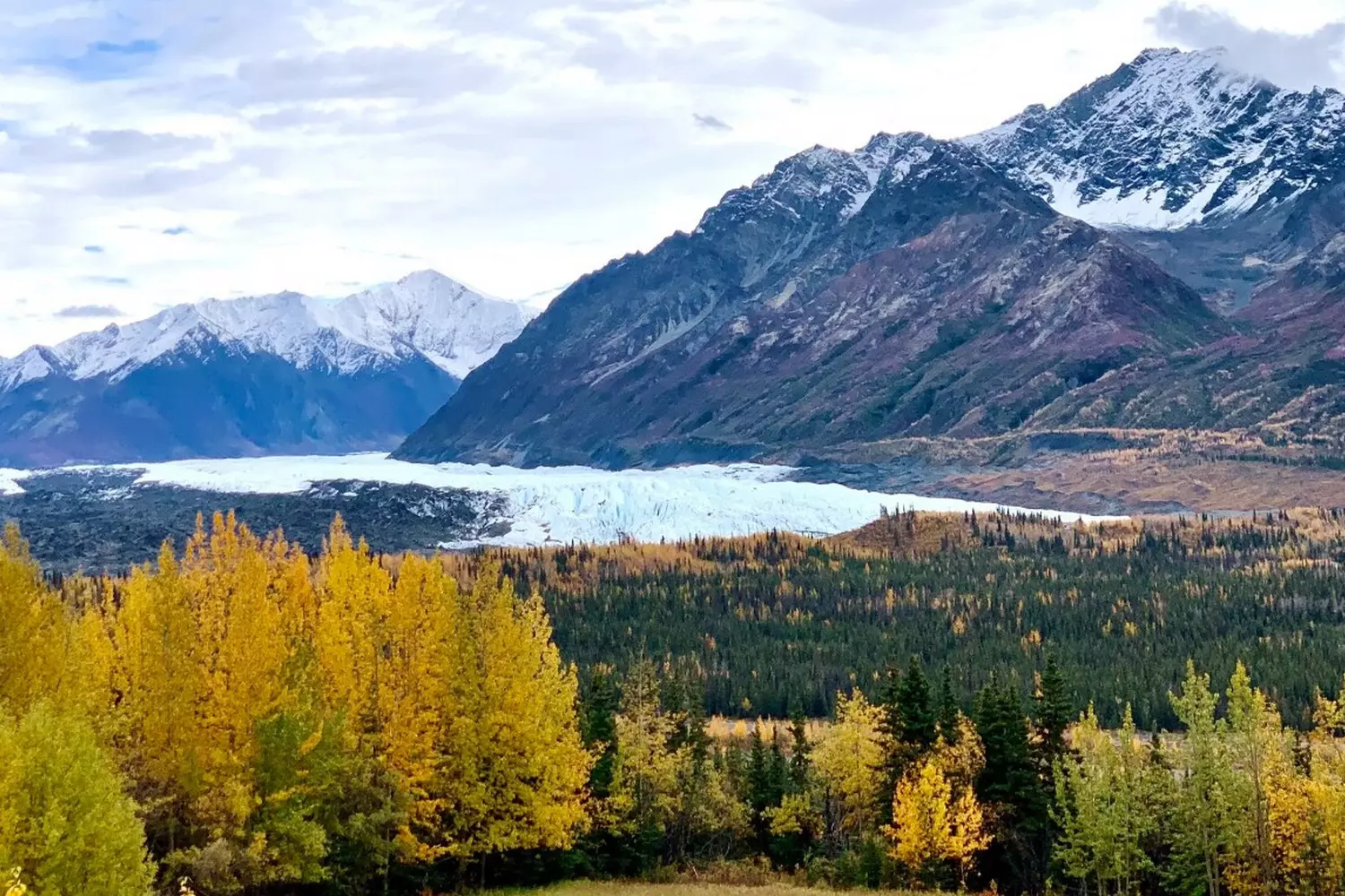 Alaska's Untamed Beauty: Landscapes That Take Your Breath Away Panoramic view of Alaska's rugged wilderness with towering snow-capped mountains, turquoise glaciers, and endless evergreen forests under a dramatic cloudy sky