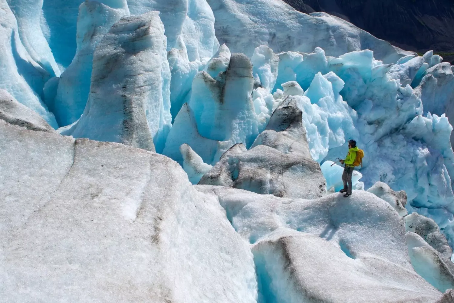 Walking on Ancient Ice: Glacier Trekking Adventures in Alaska Group of hikers with crampons carefully crossing a glacier's crevassed surface, their red jackets creating vivid contrast against the white and blue ice formations