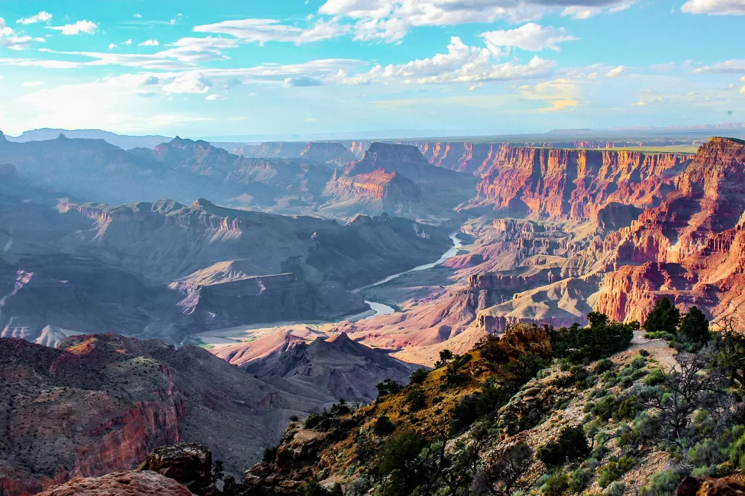 Grand Canyon, Arizona: A Majestic Masterpiece of Nature Breathtaking panoramic view of the Grand Canyon in Arizona, featuring layered red rocks beneath a bright blue sky and the Colorado River winding through the canyon floor
