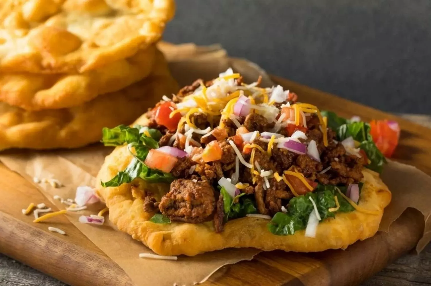 Fry Bread in Arizona: The Traditional Bread of Native Peoples A golden fry bread flatbread with traditional toppings on a plate, set against the backdrop of the Arizona desert