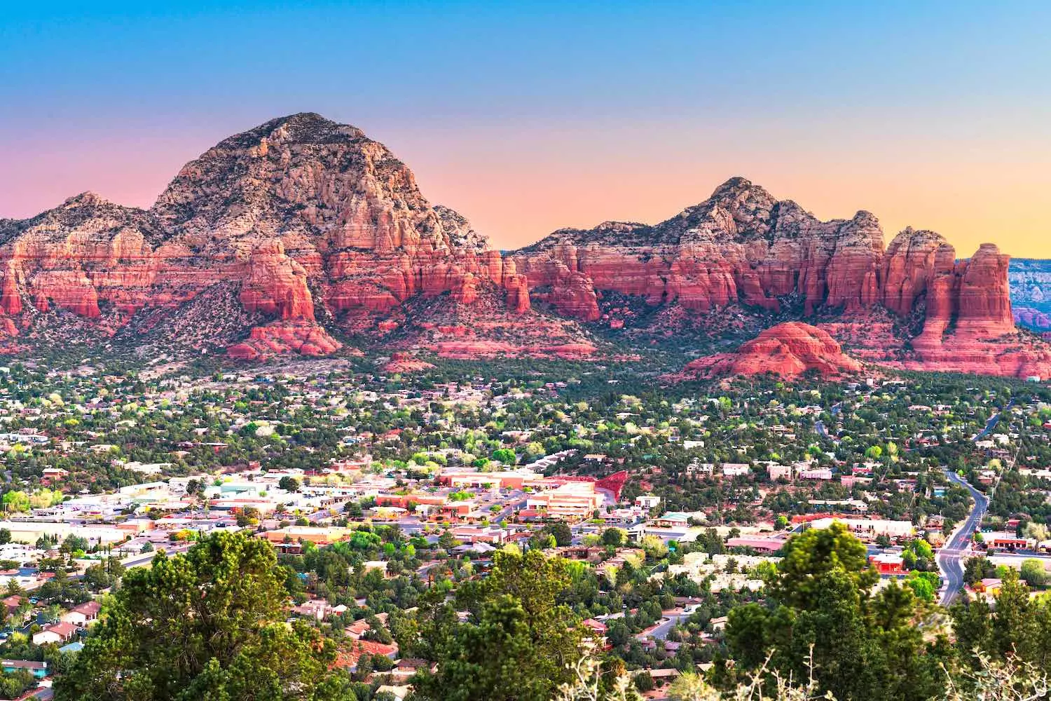 Sedona, Arizona: Land of Red Rocks and Spiritual Energy Panoramic view of Sedona’s famous red rocks — Cathedral Rock and Bell Rock — against a blue sky with greenery in the foreground