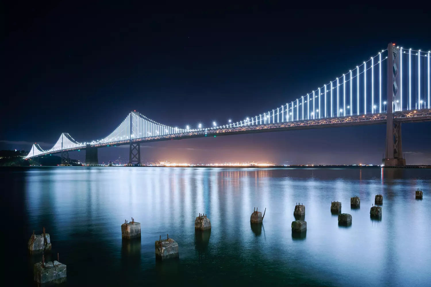 Night illumination of a California bridge, lights reflecting in dark water