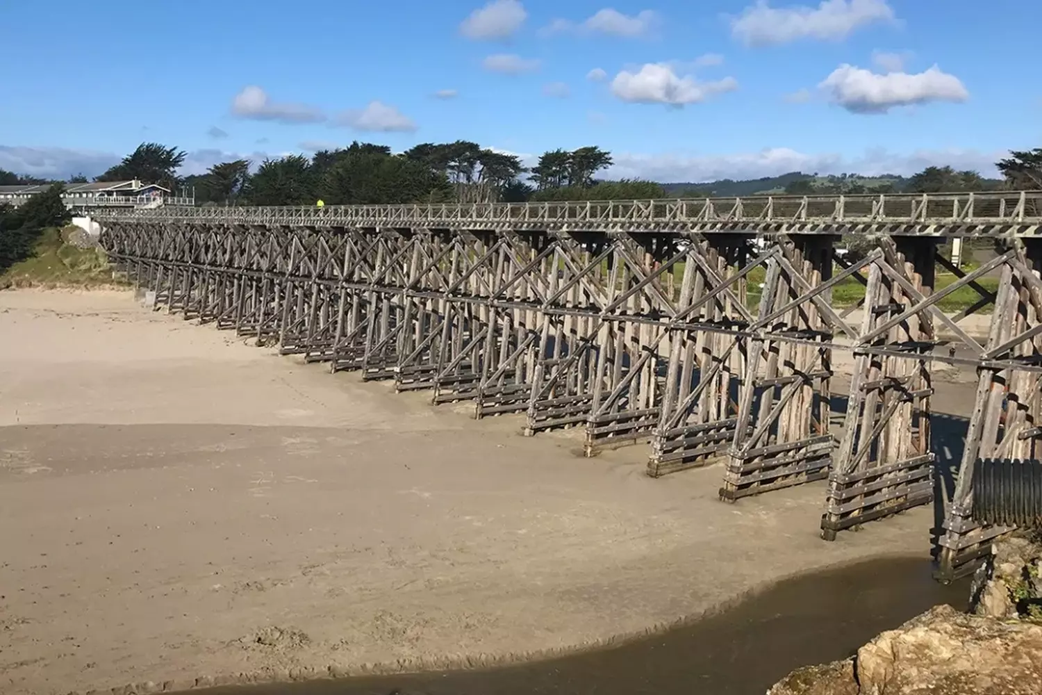 Wooden Pudding Creek Trestle bridge over Glass Beach in Fort Bragg, California, during the day with the ocean in the background