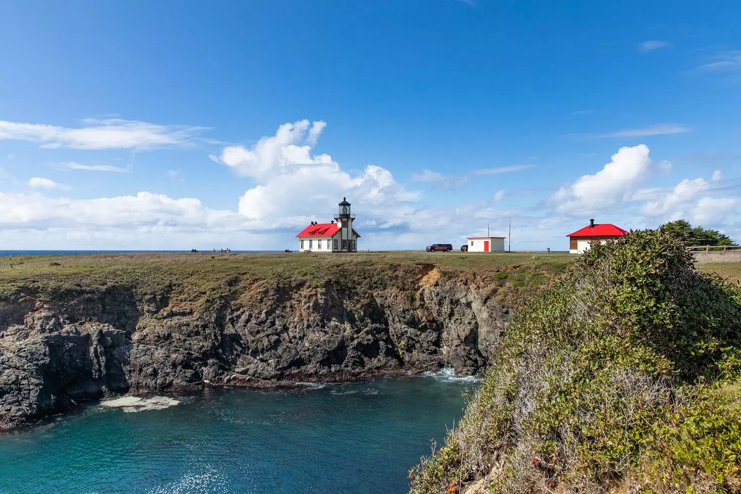 White tower of Point Cabrillo Lighthouse with lantern room and red roof against the sky