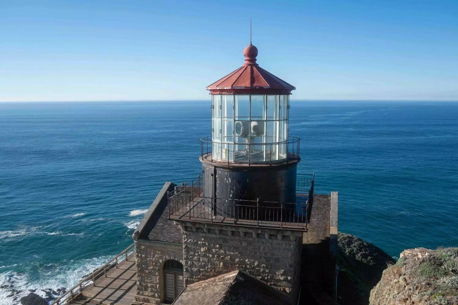 Square stone tower of Point Sur Lighthouse rising above the Pacific Ocean atop a rock in Big Sur