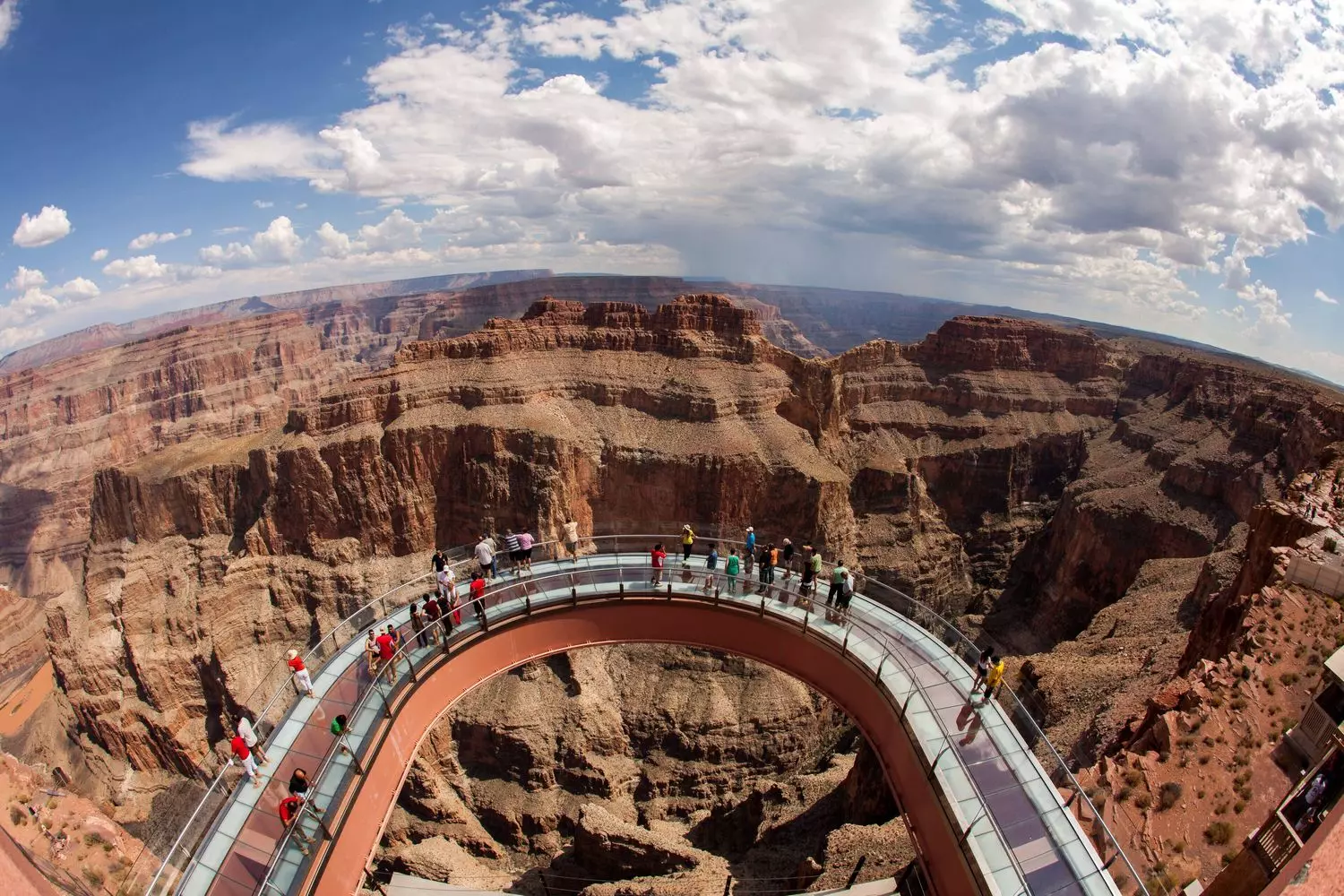 Небо под ногами: захватывающий вид со Skywalk в Гранд-Каньоне Стеклянный мост Skywalk, выступающий над краем Гранд-Каньона, с видом на отвесные скалы и реку Колорадо внизу