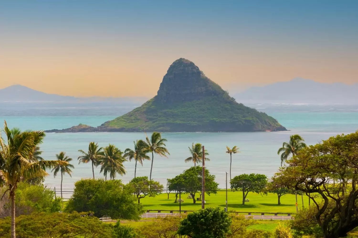 Aerial view of the Hawaiian Islands: Emerald Mountains, Turquoise Ocean and White Beaches Stunning aerial drone photo of the Hawaiian coastline showing lush green volcanic mountains meeting the bright turquoise coral reef and white sand beaches of the Pacific Ocean