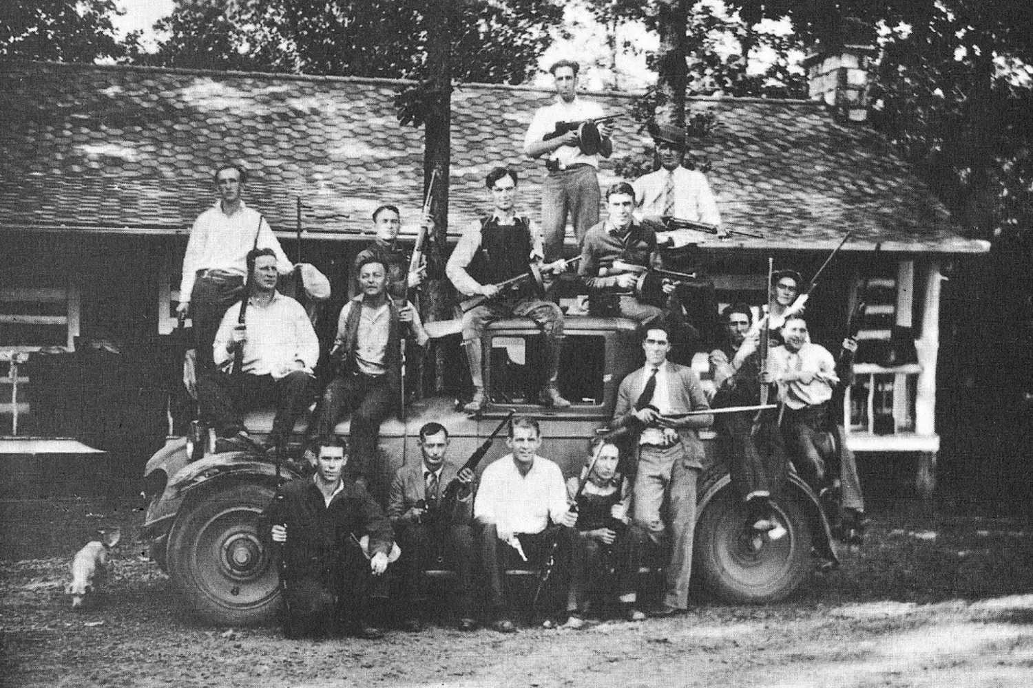 Guns & Whiskey: The Birger Gang's Reign During Illinois' Prohibition Era Historical black-and-white photo of armed bootleggers from the Birger Gang posing with rifles and Thompson submachine guns in Southern Illinois, 1924, showcasing their defiance during Prohibition