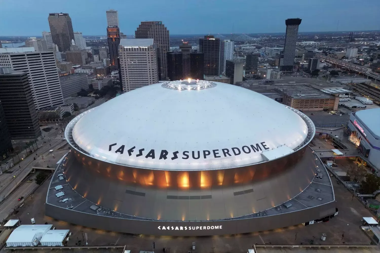 Вид сверху на стадион Superdome во время Essence Festival, тысячи зрителей на трибунах, сцена в центре с ярким светом, масштабное шоу