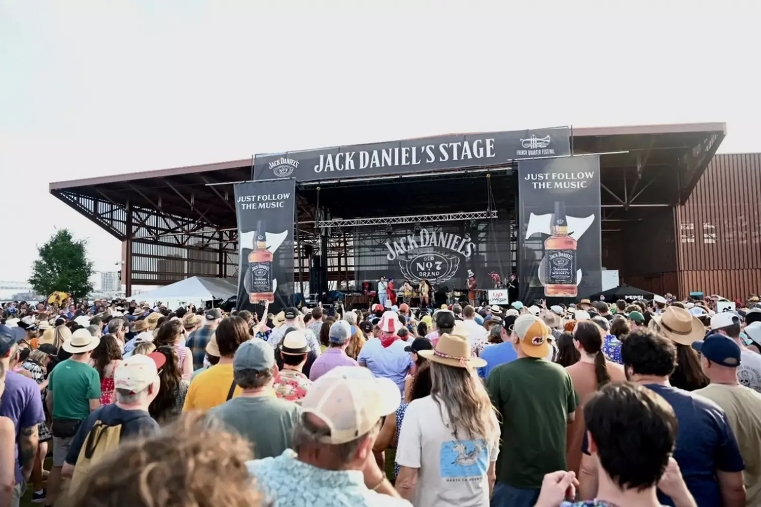 Сцена Jack Daniel's на French Quarter Festival в Новом Орлеане — музыканты выступают перед толпой на набережной Миссисипи