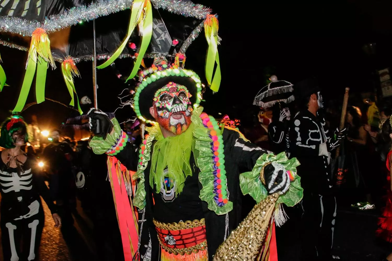 Участник Krewe of Boo в костюме мексиканского черепа Catrina с ярким макияжем и цветочным венком на хэллоуинском параде в Новом Орлеане