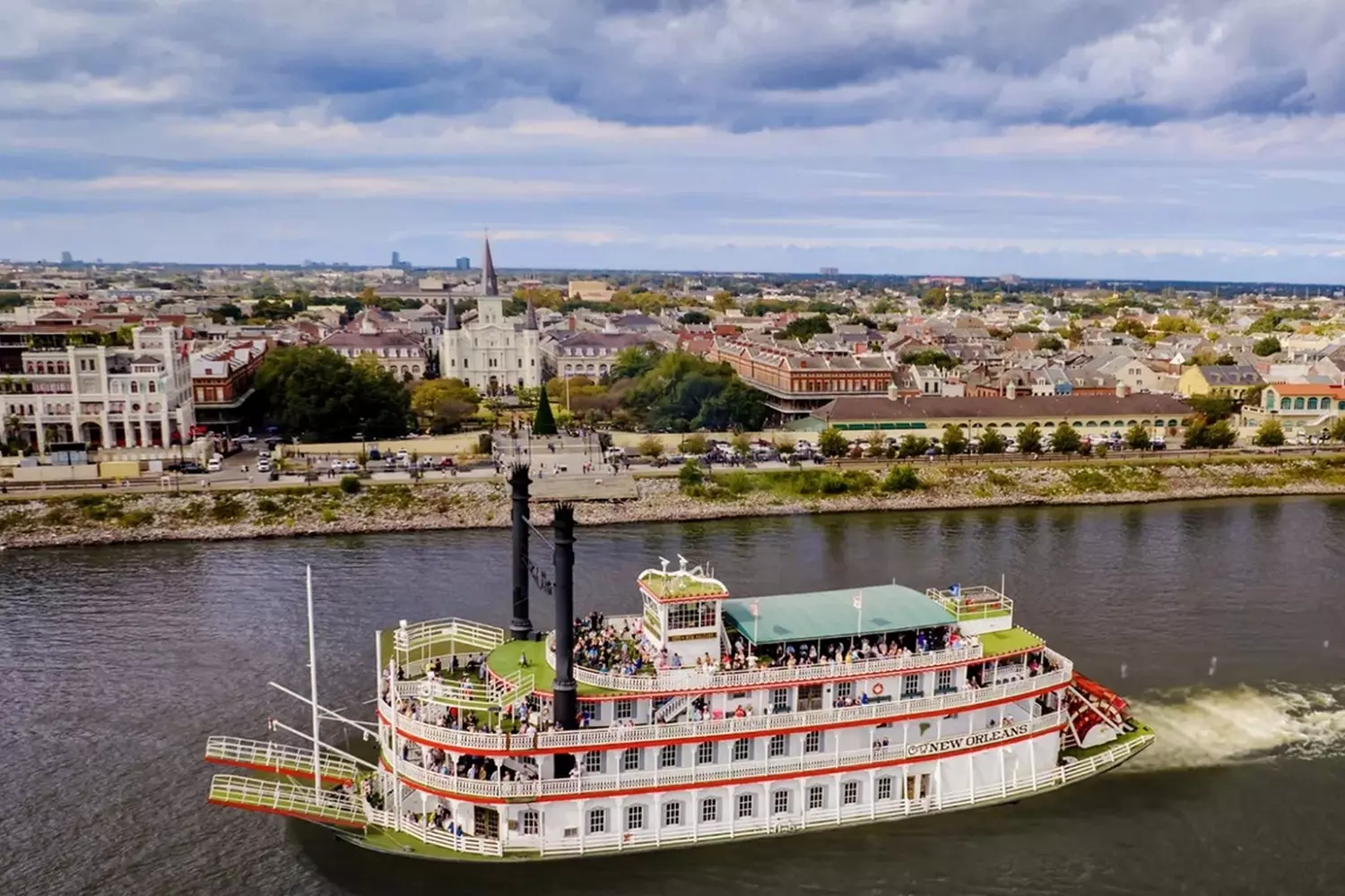 Легендарный колёсный пароход Steamboat Natchez на реке Миссисипи на фоне панорамы Нового Орлеана с небоскрёбами и городской застройкой