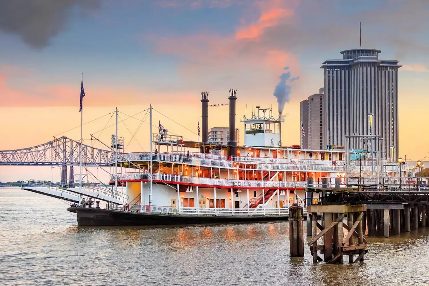 Легендарный колёсный пароход Steamboat Natchez на реке Миссисипи на фоне моста и высотных зданий Нового Орлеана, Луизиана