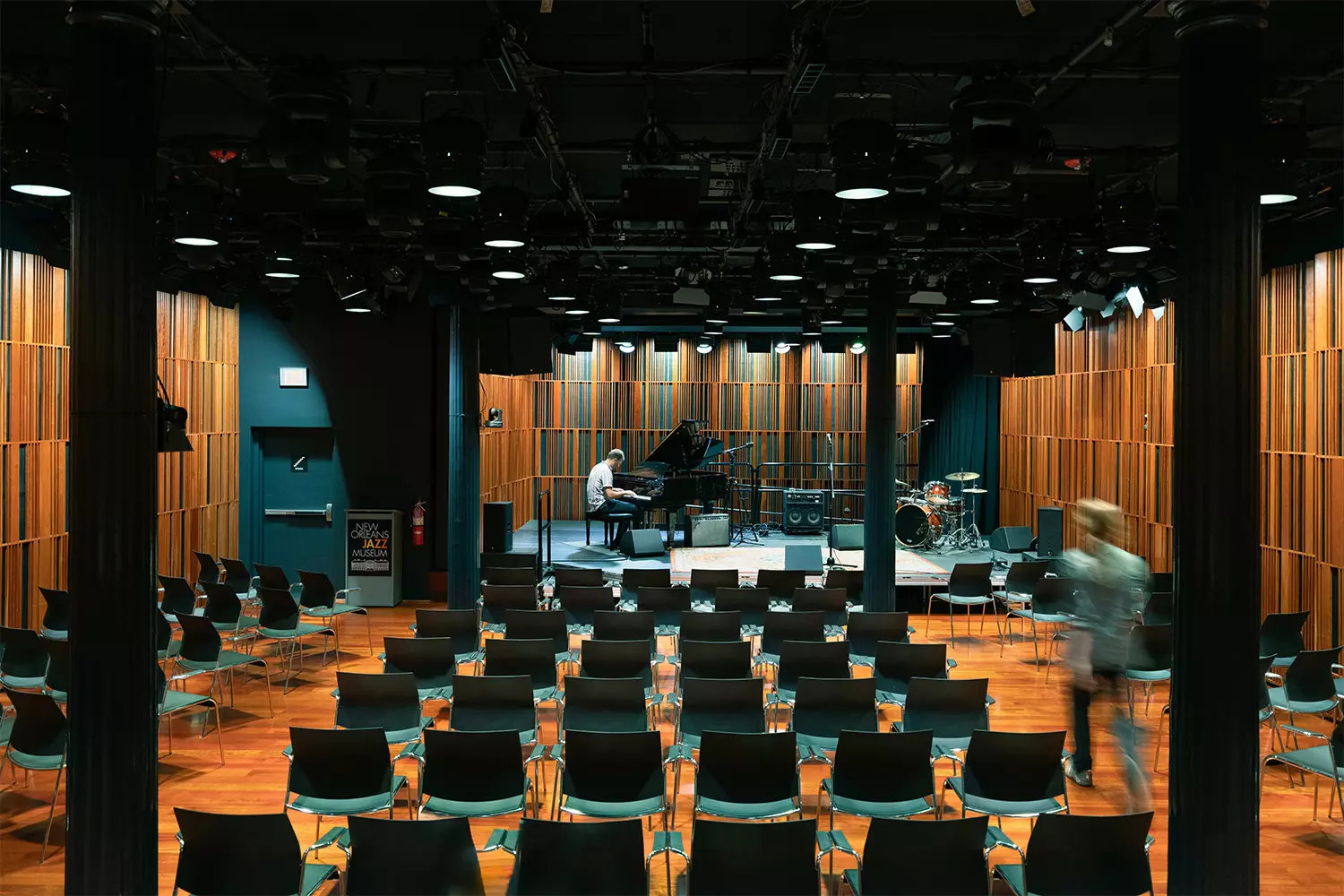 Небольшой концертный зал внутри New Orleans Jazz Museum: сцена, ряды стульев, музыкальное освещение и акустические панели