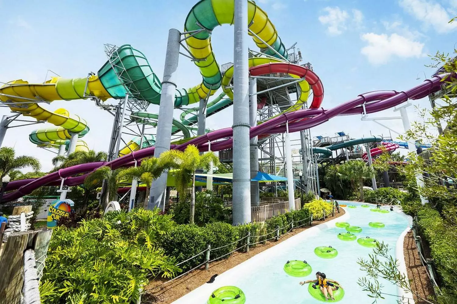 Thrills & Spills: Adventure Island Water Park Escapades Colorful water slides and tropical palm trees at Adventure Island water park, with guests splashing in pools and riding the twisting Vanish Point drop slide under sunny Florida skies
