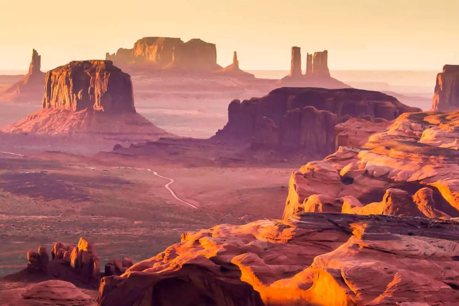 Золотой час: Долина Монументов на закате Скалы-останцы и месы Долины Монументов в силуэте на фоне яркого оранжево-фиолетового закатного неба