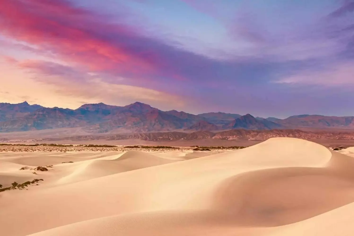 Endless Beauty: Nevada's Desert Landscapes Vast desert scenery in Nevada with golden sand dunes, rugged mountains, and clear blue skies – a stunning showcase of nature's raw beauty