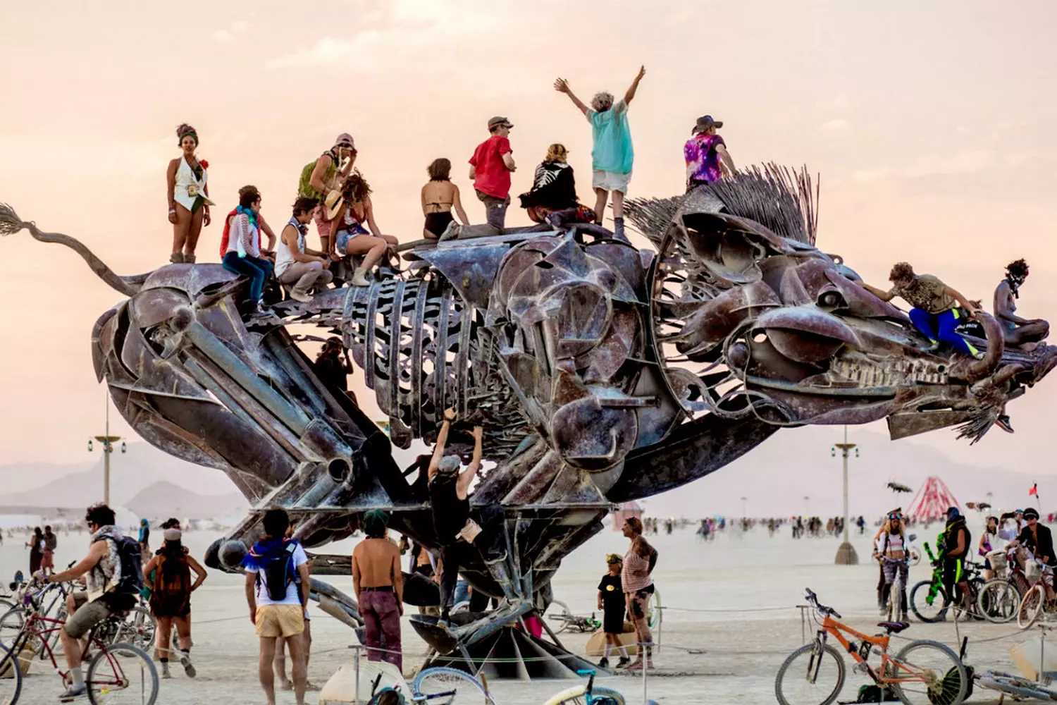 Participants on top of a boar art installation at Burning Man festival People climbing on a wild boar sculpture at Burning Man