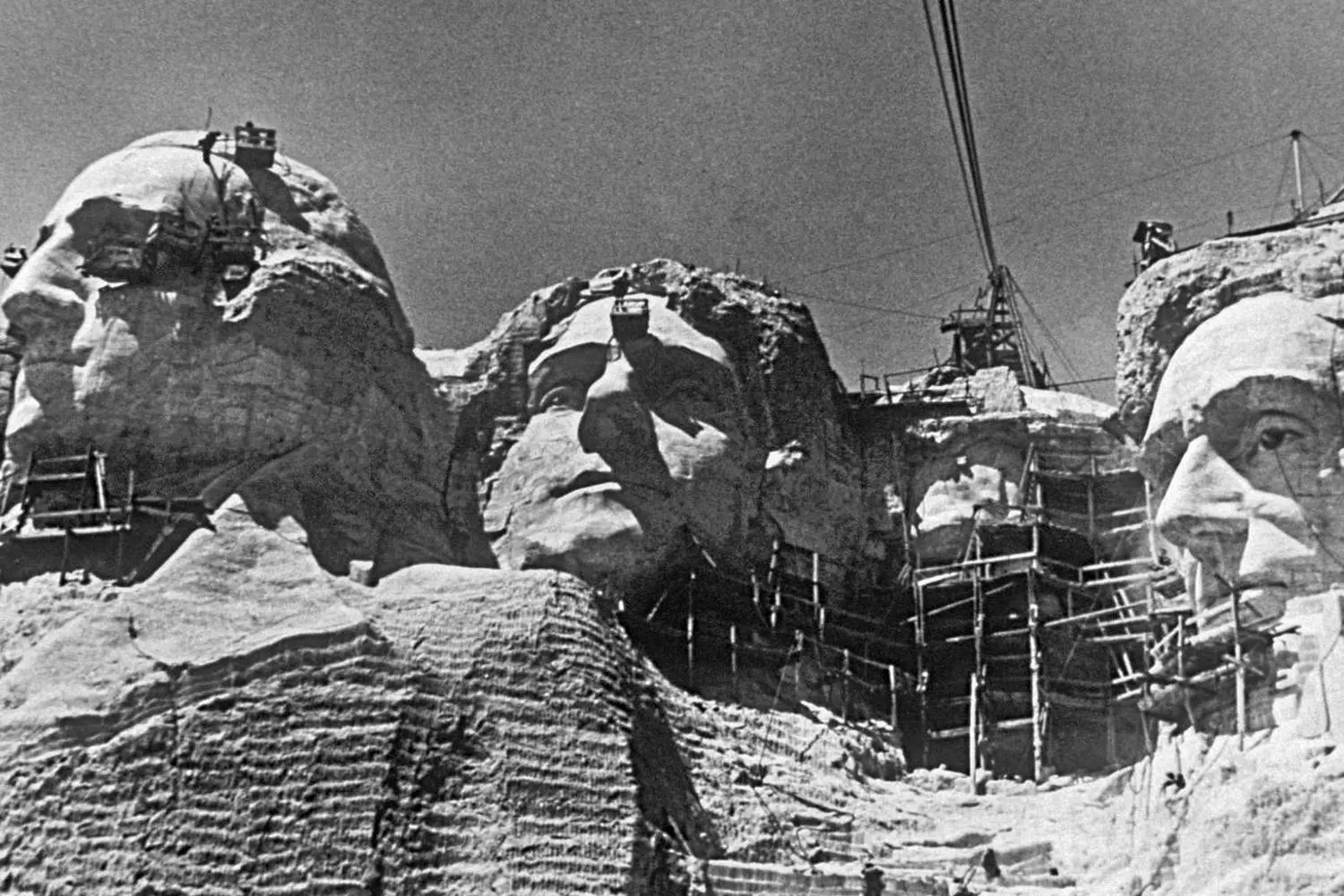 Гора Рашмор в процессе создания: как строили легендарный монумент (1927-1941) Историческое чёрно-белое фото: рабочие высекают лица президентов на горе Рашмор с помощью верёвок и пневматических инструментов в период строительства