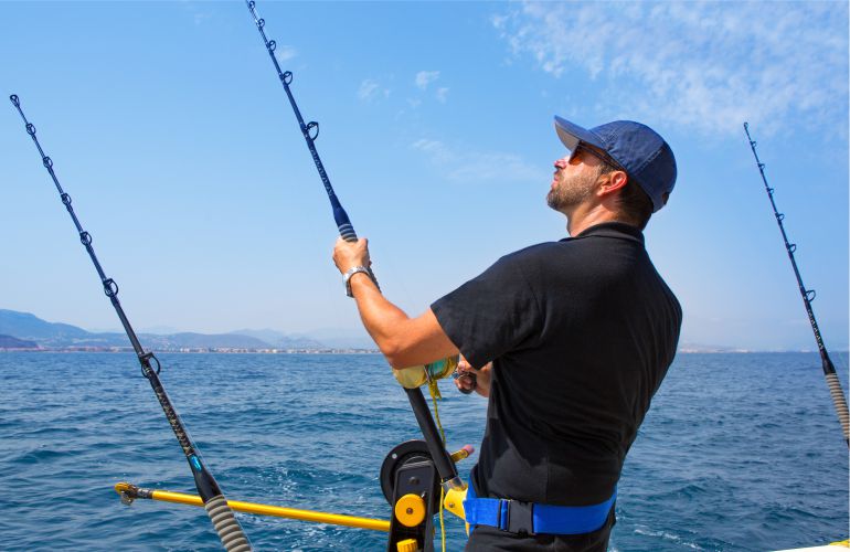 Sea fishing in the USA - photo man fisherman catches fish for a fishing rod in the ocean - American Butler