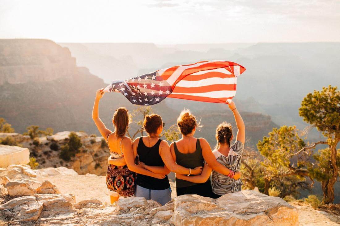 Какие бывают визы в США — фото туристок с американским флагом — American Butler